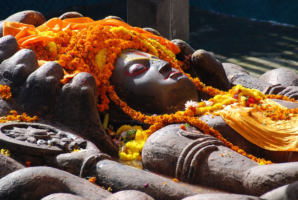 Kathmandu Valley 1 Budhanikantha 3 Sleeping Vishnu Head Close Up Budhanilkantha Narayan (Sleeping Vishnu) lies peacefully on the coils of the multi-headed snake Ananta. The snakes 11 hooded heads rise protectively around Narayans head. Vishnus four hands hold the four symbols of Vishnu: chakra disk(representing the mind), a conch shell (the four elements), a mace (primeval knowledge), and a lotus seed (the moving universe).